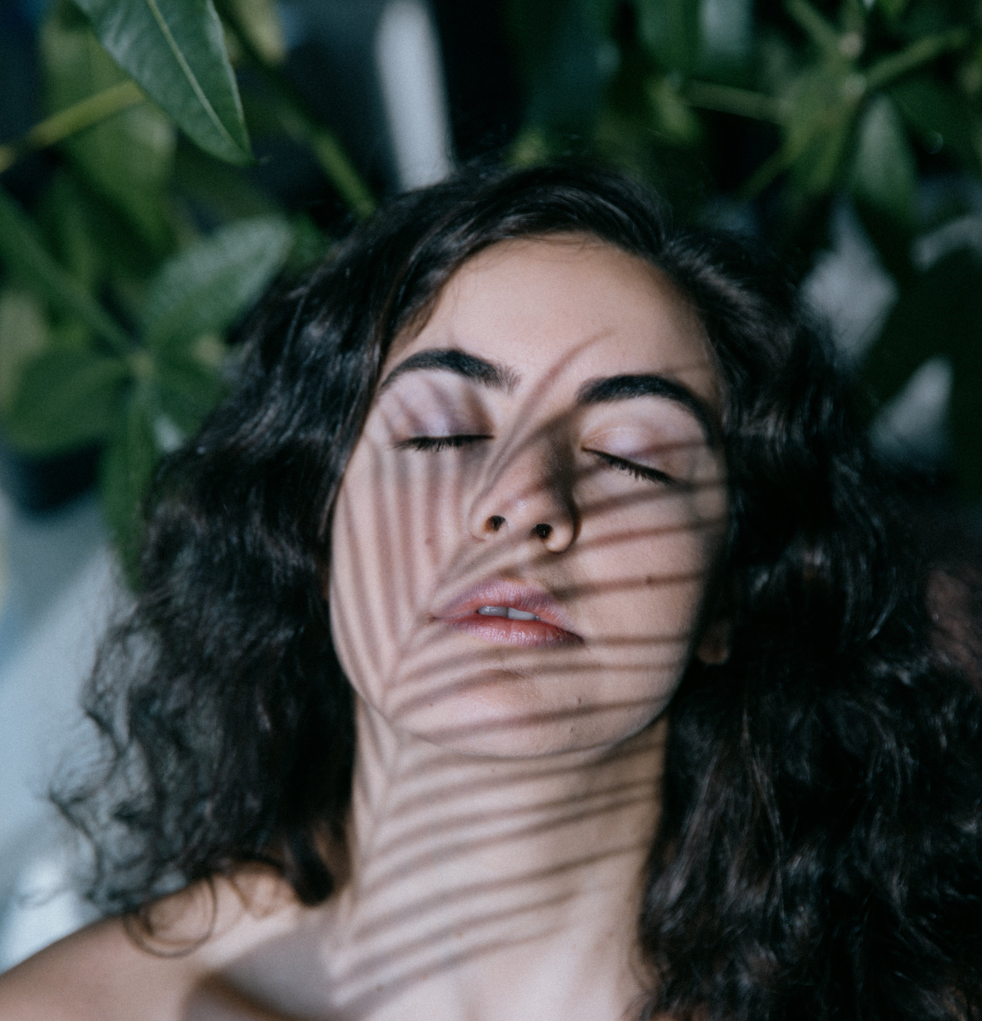 eyes-closed-while-a-plant-casts-a-shadow-on-their-face.jpg